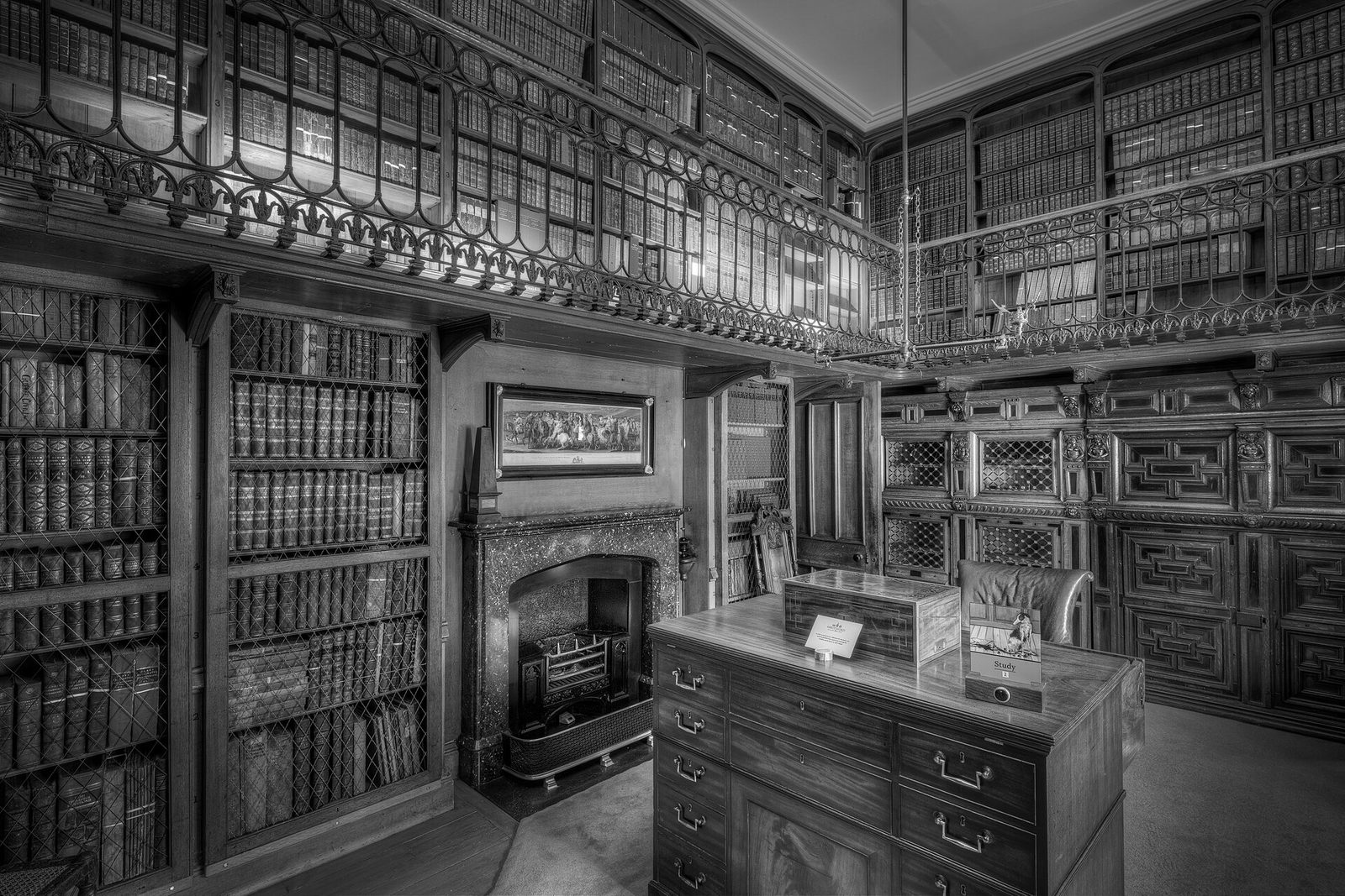 A dark wood-panelled study with a writing desk and bookcases